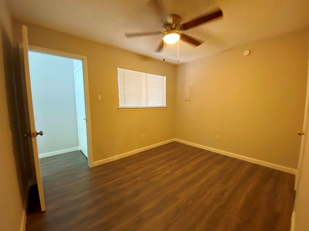 1840 Burton Drive, Unit 128 Austin, TX 78741 - Photo 15 of 22 an empty room with wooden floor fan and windows