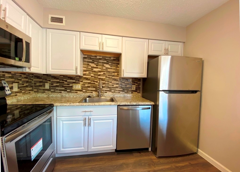 1840 Burton Drive, Unit 128 Austin, TX 78741 - Photo 7 of 22 a kitchen with stainless steel appliances granite countertop a refrigerator a stove a sink and a microwave