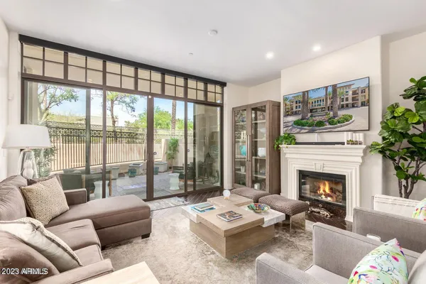 a living room with furniture a fireplace and a floor to ceiling window