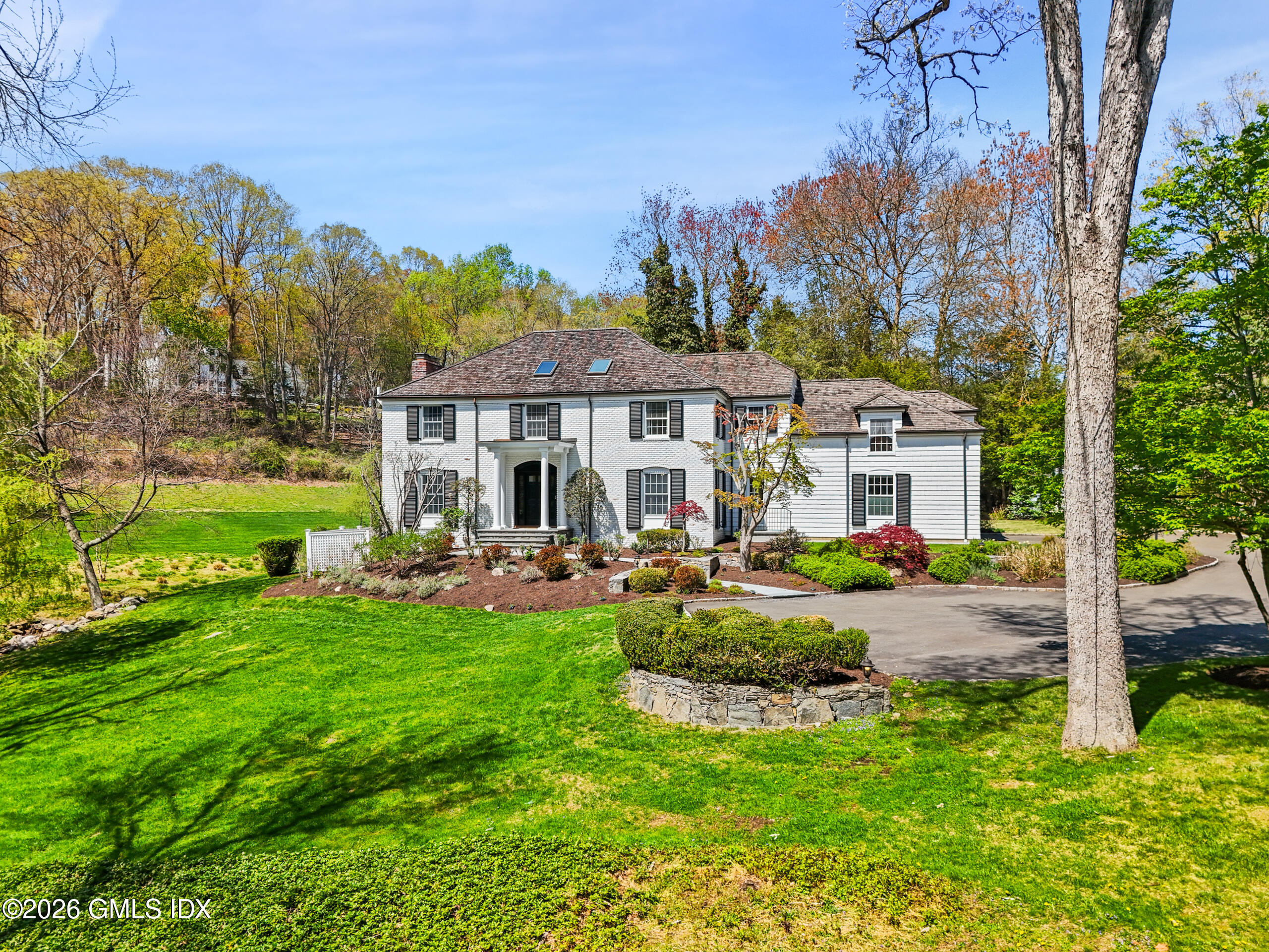a front view of a house with garden and trees