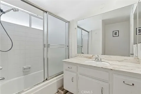 a bathroom with a granite countertop sink a mirror a vanity and a shower