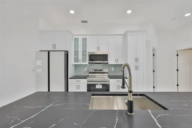 a kitchen with white cabinets and stainless steel appliances