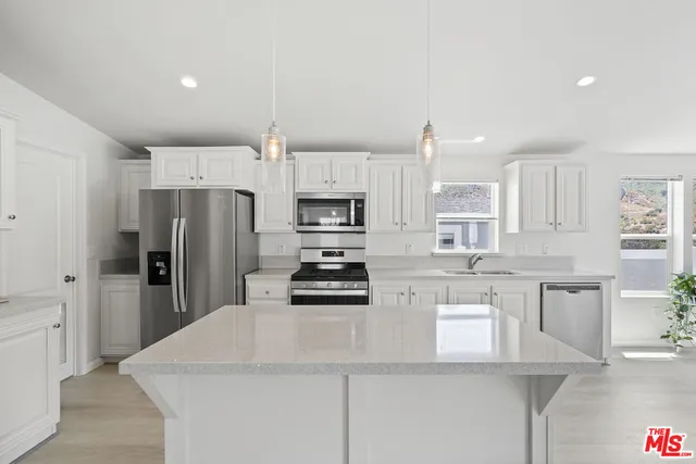 a kitchen with stainless steel appliances a refrigerator sink and microwave