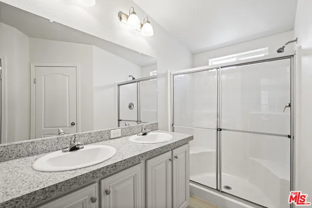 a bathroom with a granite countertop sink mirror and a shower
