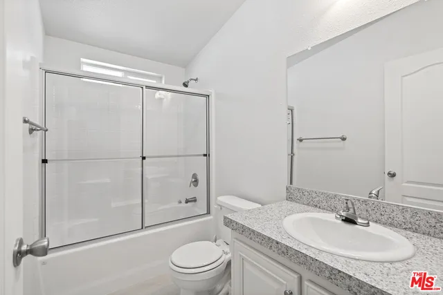a bathroom with a granite countertop sink toilet mirror and shower