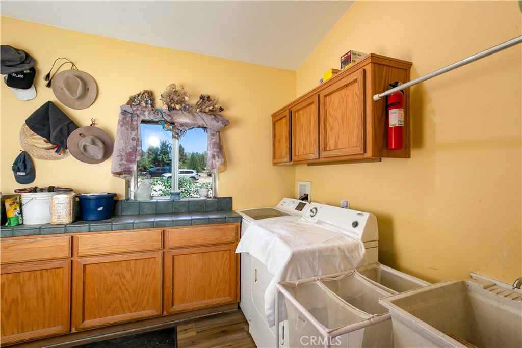 10960 Steinhoff Road Frazier Park, CA 93225 - Photo 29 of 46 The home's dedicated laundry and utility space. This practical room features oak upper and lower cabinetry, a built-in utility sink with counter space, laundry hookups, and soft yellow-toned walls complete with a convenient wall-mounted coat and hat rack.