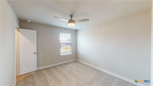an empty room with a window and ceiling fan