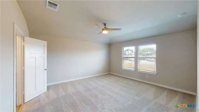 an empty room with chandelier fan and windows
