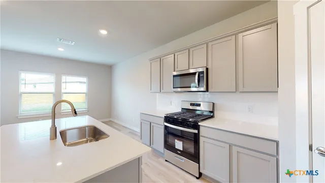 a kitchen with white cabinets a sink and appliances