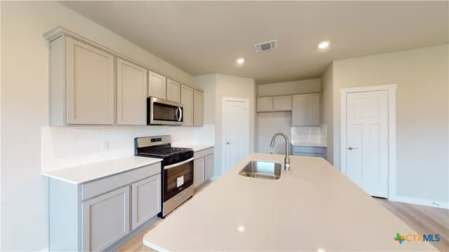 a kitchen with granite countertop white cabinets and stainless steel appliances