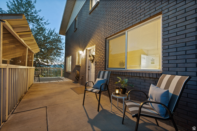 9750 Indian Ridge Drive Sandy, UT 84092 - Photo 6 of 40 Concrete patio area featuring a dark brick exterior, white trim, and a screened-in porch with a wood-slatted roof