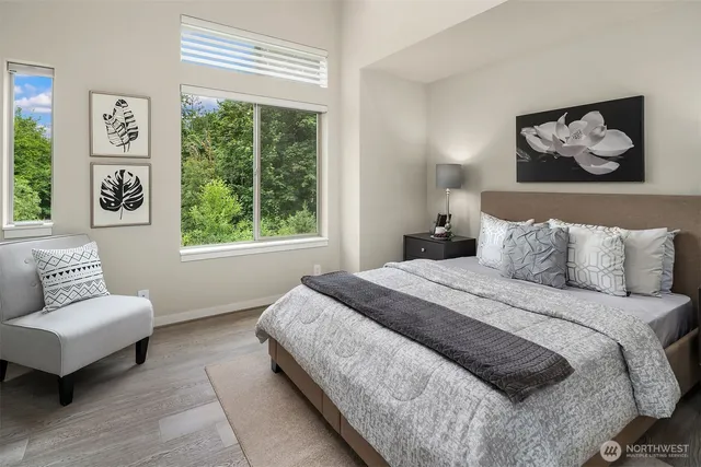 a bedroom with a bed painting on wall and a large window