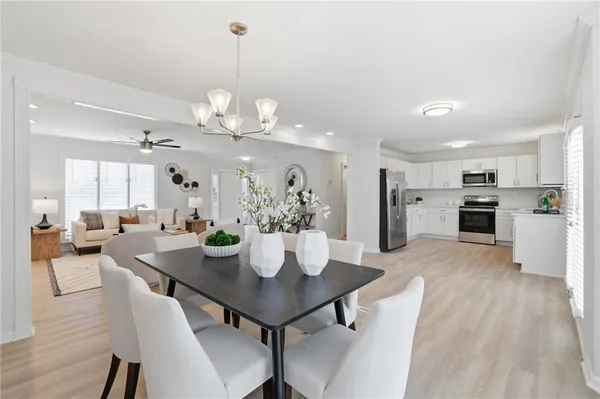 a view of a dining room and livingroom view with furniture wooden floor a chandelier