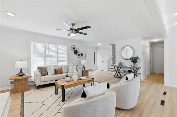 a living room with furniture a chandelier fan and a large window