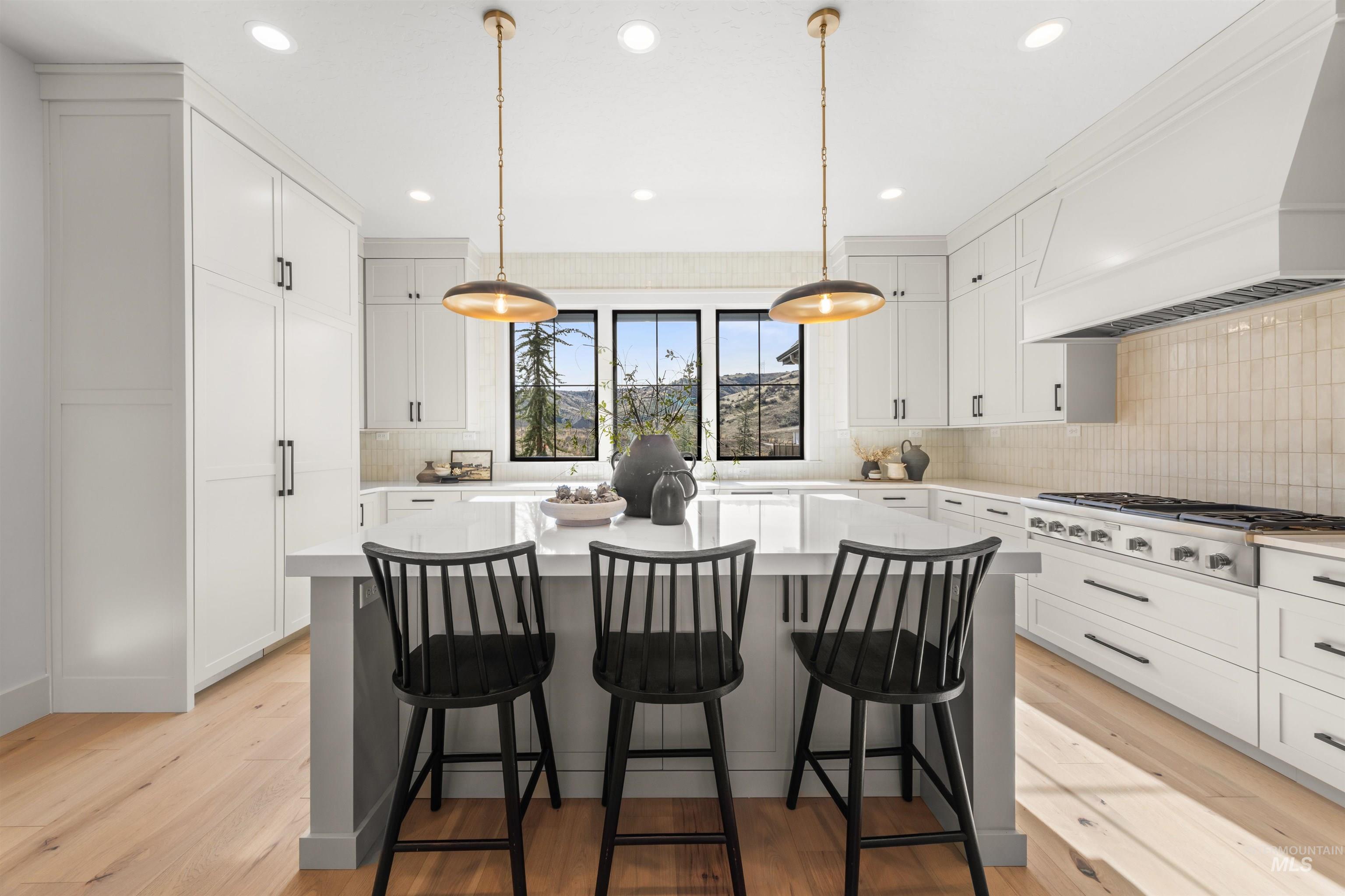 10968 North Elk Ridge Place Boise, ID 83714 - Photo 12 of 49 Kitchen with a kitchen island, a breakfast bar area, white cabinets, and hanging light fixtures