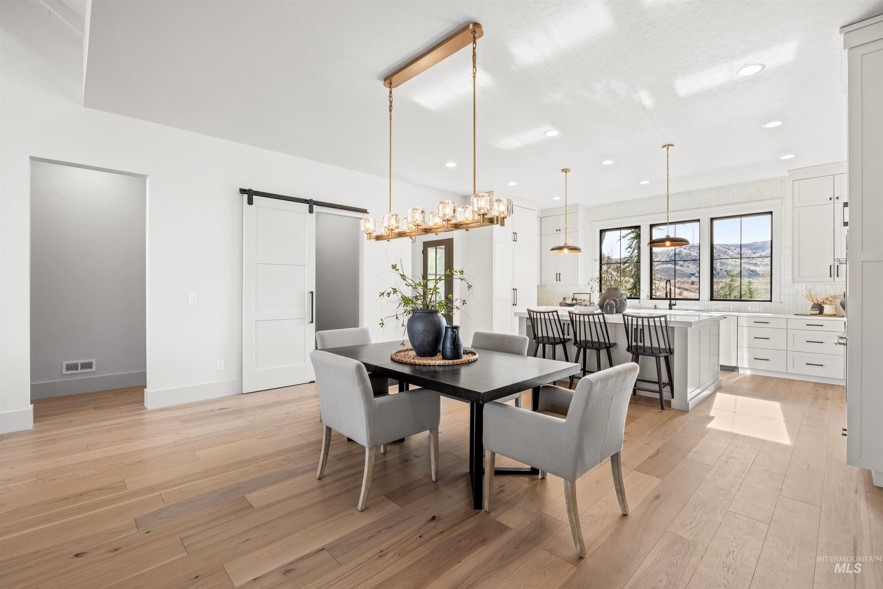 10968 North Elk Ridge Place Boise, ID 83714 - Photo 14 of 49 Dining space featuring a barn door, light wood finished floors, and hanging lights