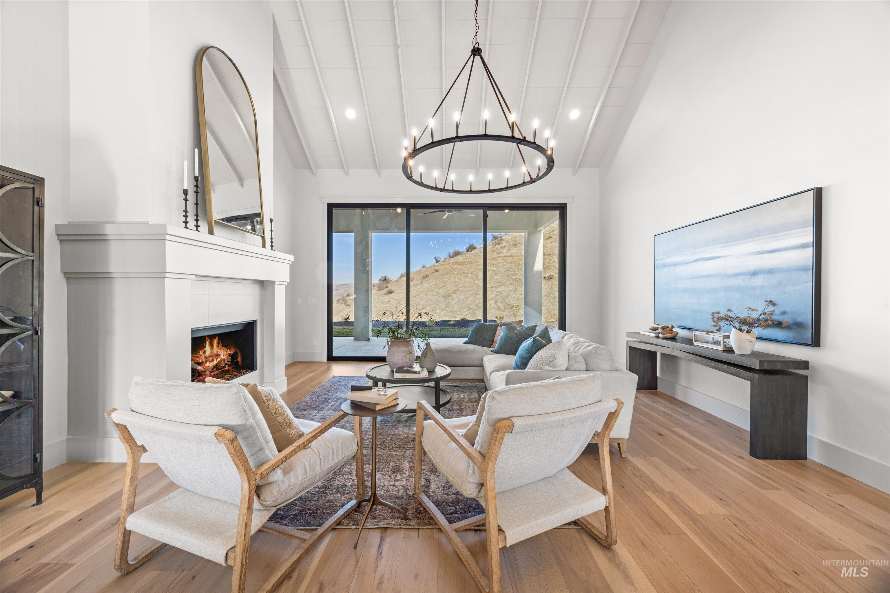 10968 North Elk Ridge Place Boise, ID 83714 - Photo 16 of 49 Living area featuring a lit fireplace, lofted ceiling, light wood-style flooring, and a chandelier
