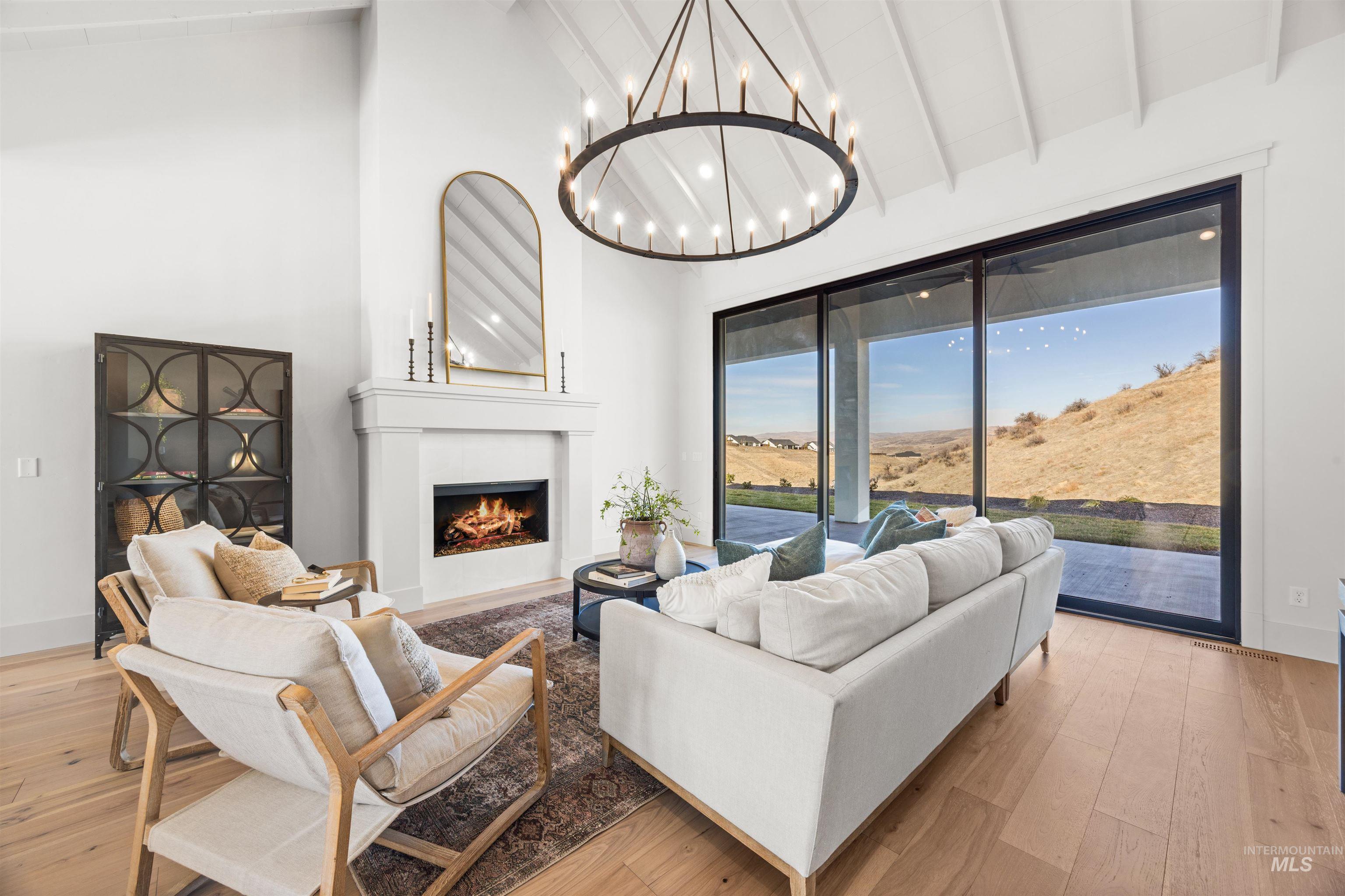10968 North Elk Ridge Place Boise, ID 83714 - Photo 17 of 49 Living area with light wood finished floors, vaulted ceiling, a warm lit fireplace, and a chandelier