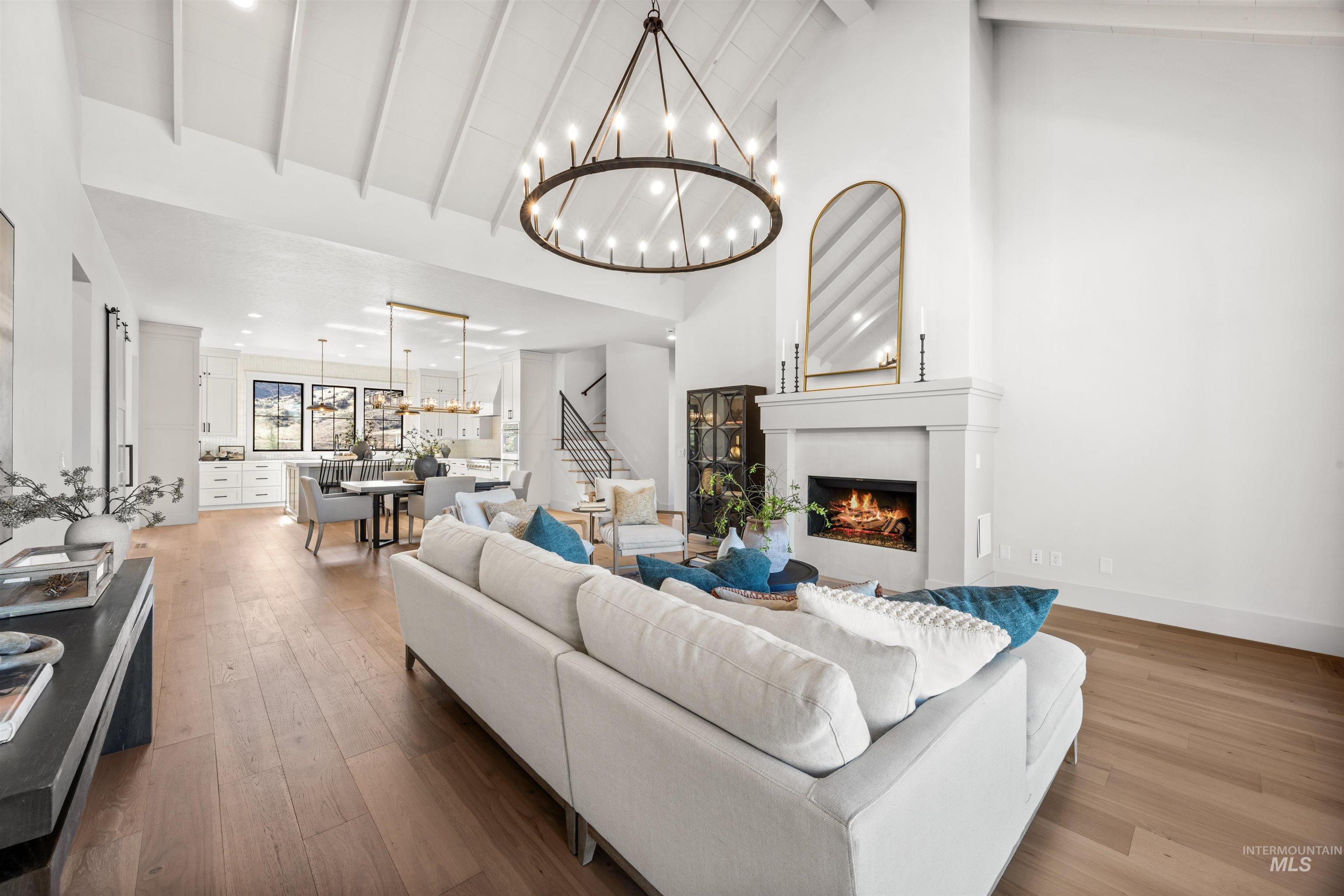 10968 North Elk Ridge Place Boise, ID 83714 - Photo 18 of 49 Living room featuring hardwood / wood-style floors, a lit fireplace, vaulted ceiling, and suspended lighting