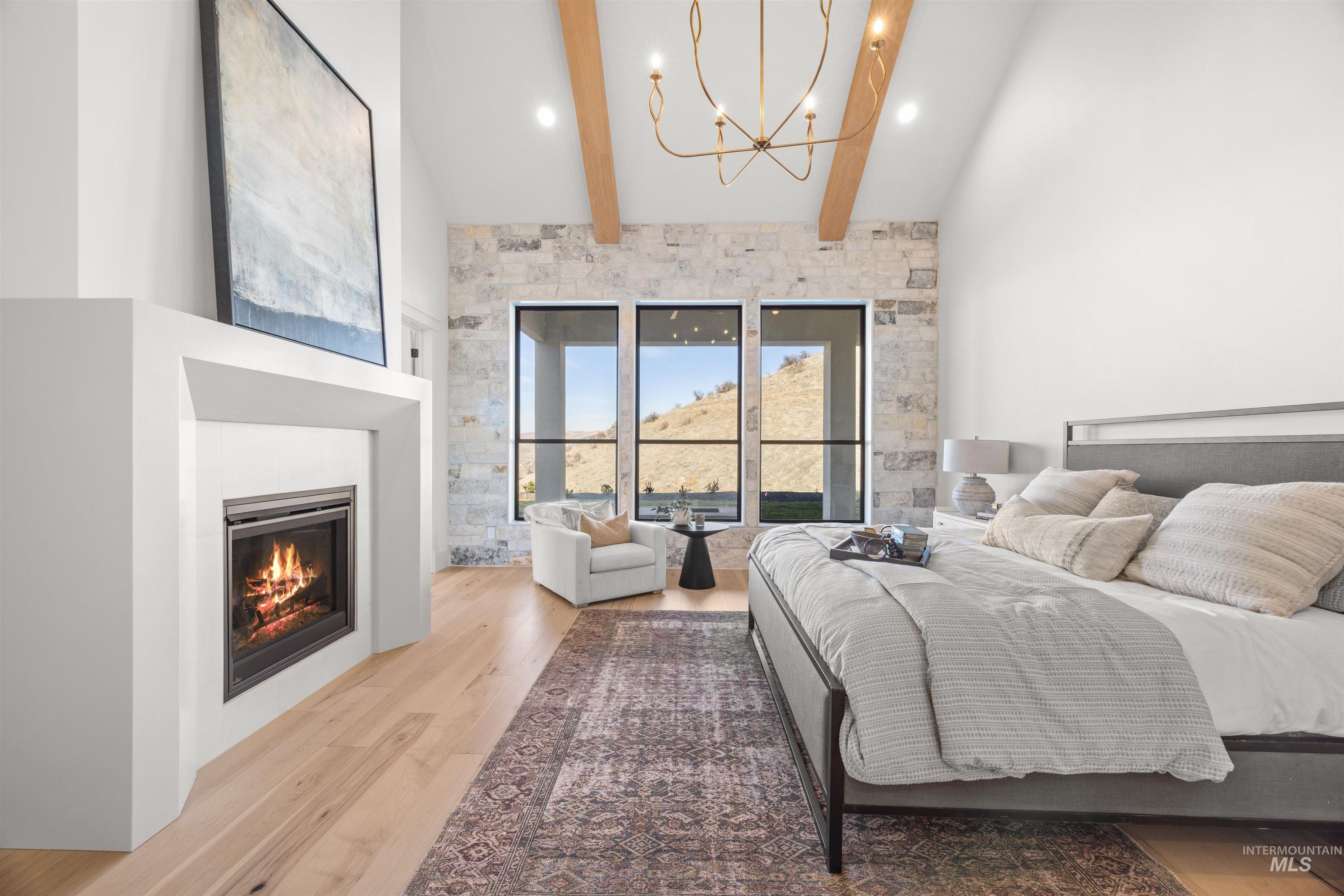 10968 North Elk Ridge Place Boise, ID 83714 - Photo 20 of 49 Bedroom featuring a glass covered fireplace, light wood-type flooring, a chandelier, and vaulted ceiling