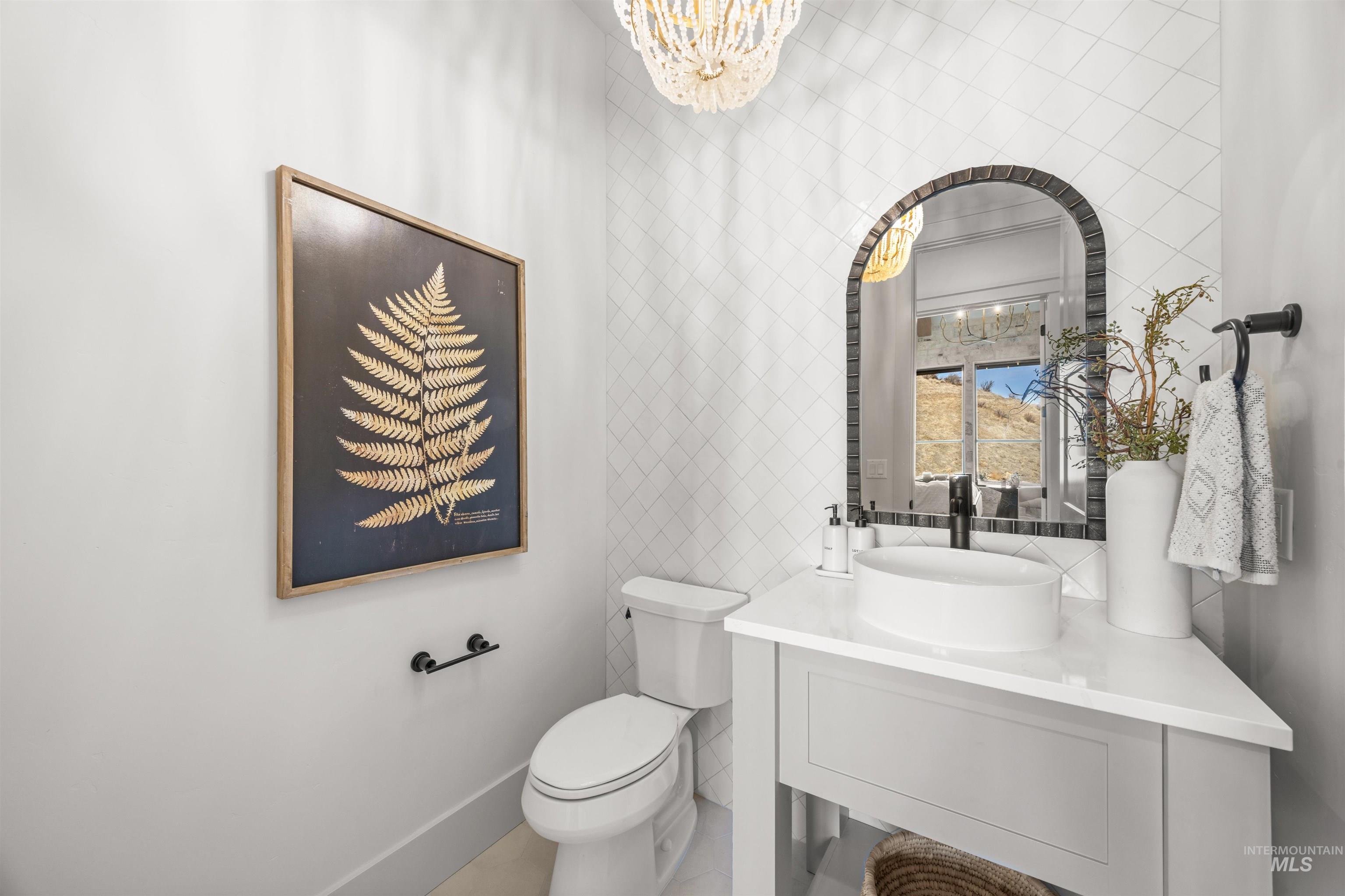 10968 North Elk Ridge Place Boise, ID 83714 - Photo 31 of 49 Half bathroom with tile walls, vanity, and a chandelier