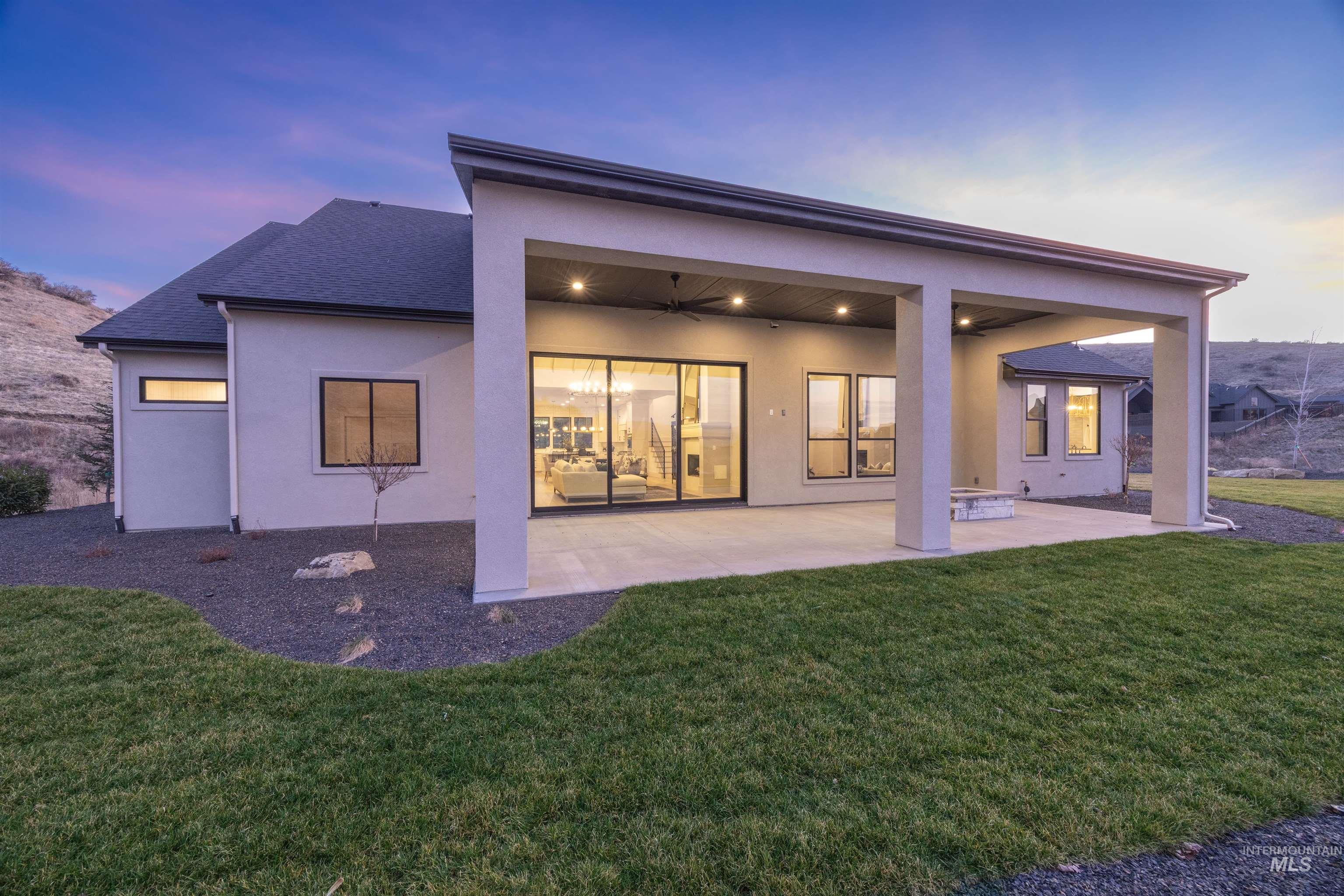 10968 North Elk Ridge Place Boise, ID 83714 - Photo 40 of 49 Back of property at dusk with a patio area, stucco siding, ceiling fan, and a yard