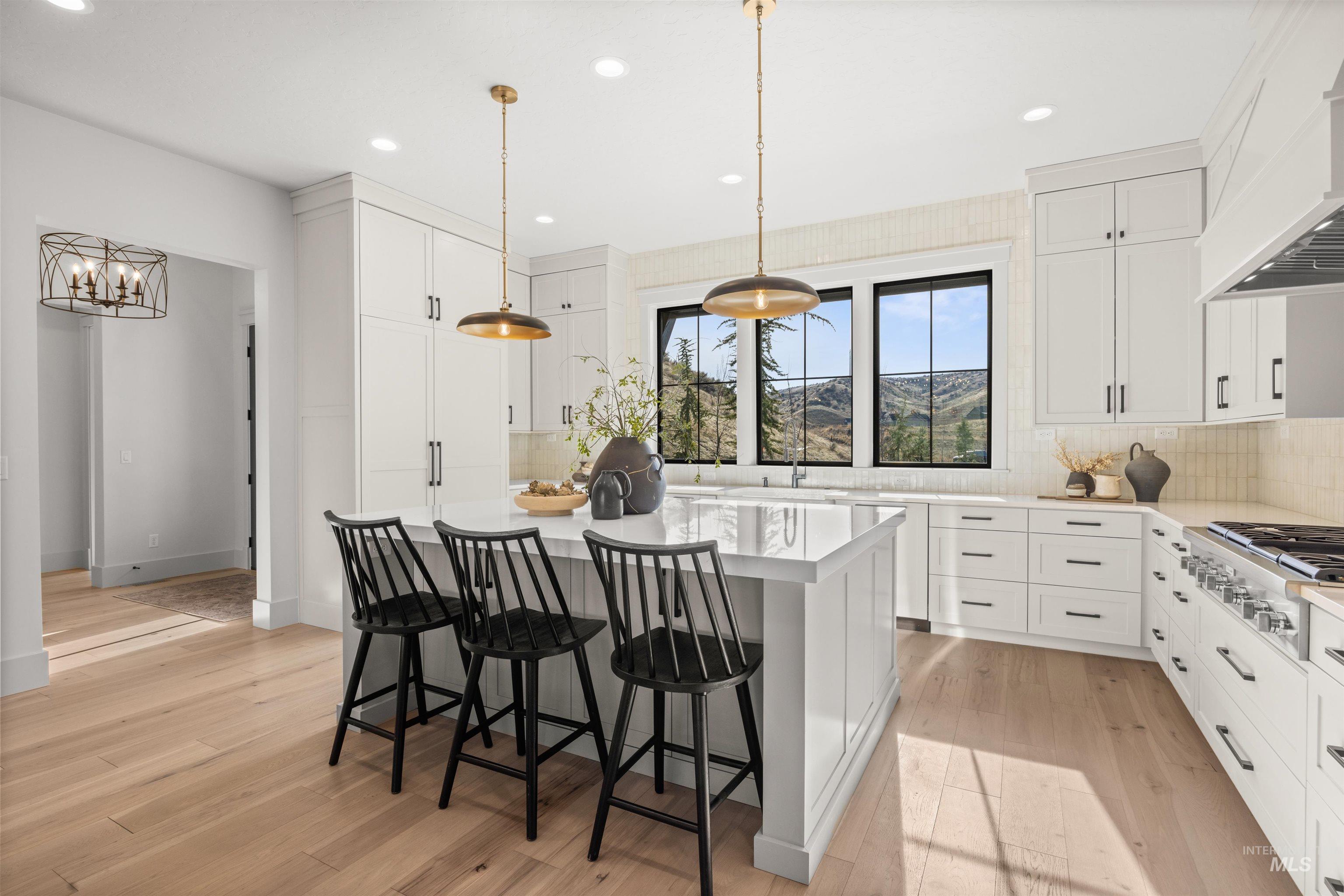 10968 North Elk Ridge Place Boise, ID 83714 - Photo 6 of 49 Kitchen with a kitchen island, white cabinets, tasteful backsplash, pendant lighting, and light wood-type flooring