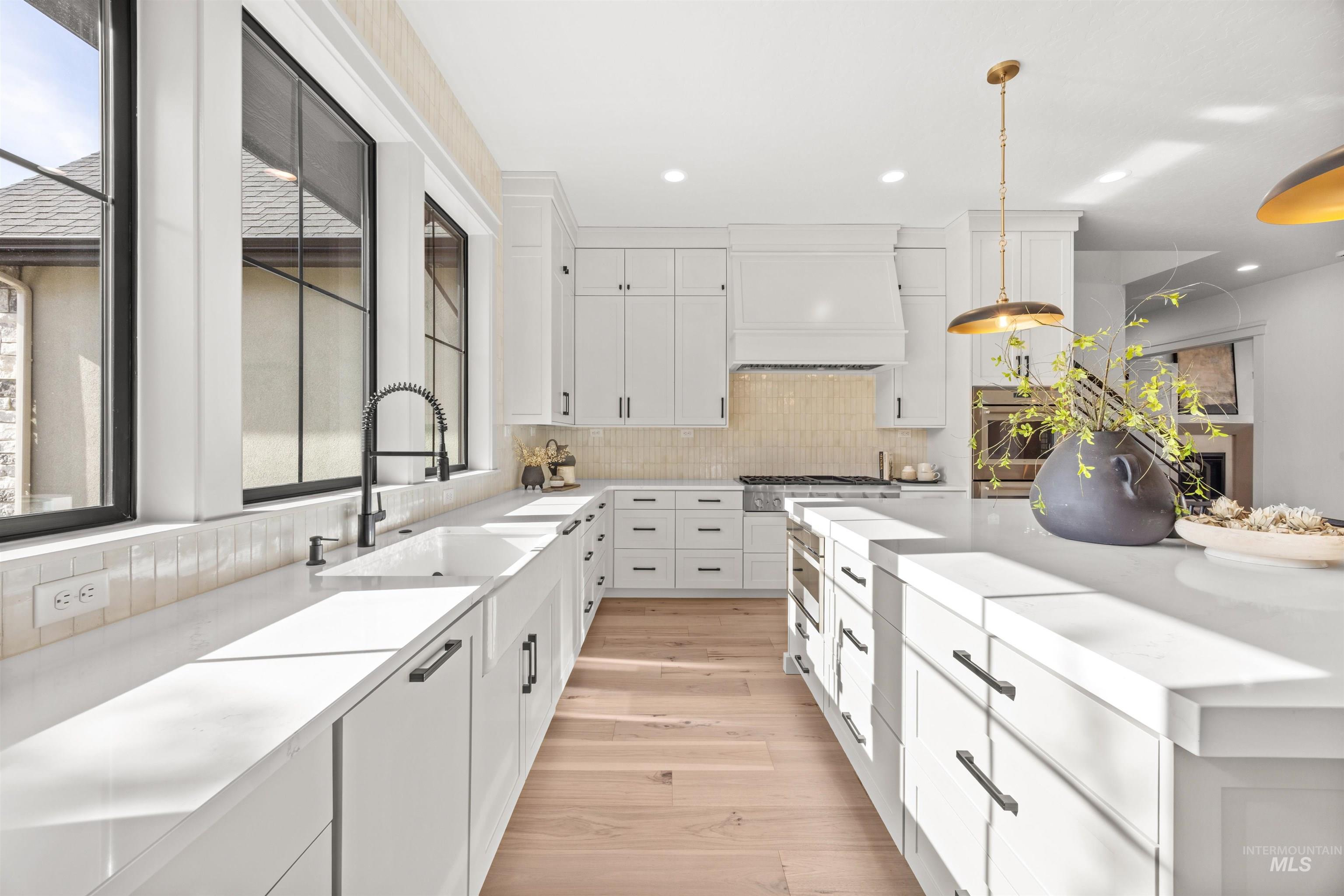 10968 North Elk Ridge Place Boise, ID 83714 - Photo 10 of 49 Kitchen featuring decorative light fixtures, white cabinets, light wood finished floors, and light stone counters