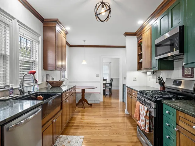 a kitchen with stainless steel appliances granite countertop a stove a sink dishwasher a dining table and chairs with wooden floor