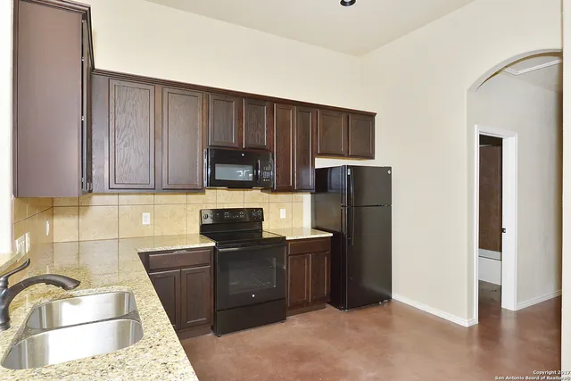 a kitchen with granite countertop wooden cabinets and refrigerator
