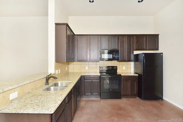 a kitchen with granite countertop a sink stove and refrigerator
