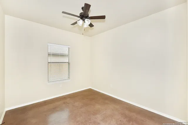 an empty room with a window and a fan