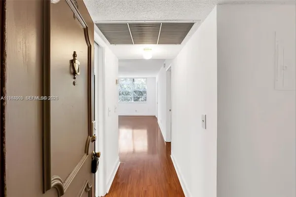 a view of a hallway with wooden floor and a bathroom