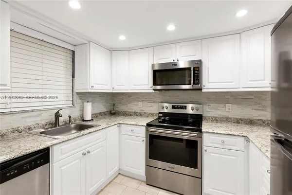 a kitchen with granite countertop a stove sink and microwave