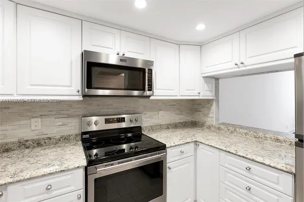 a kitchen with granite countertop white cabinets and appliances