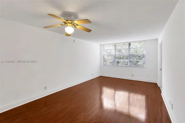 a view of empty room with wooden floor and fan
