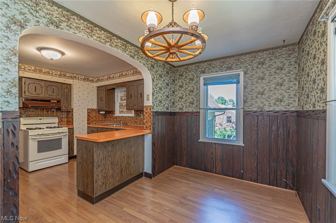 8358 Ridge Road North Royalton, OH 44133 - Photo 14 of 25 Kitchen with white gas range oven, a chandelier, custom exhaust hood, light countertops, backsplash, and light hardwood floors
