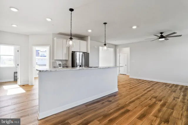 a view of a kitchen with wooden floor and a ceiling fan