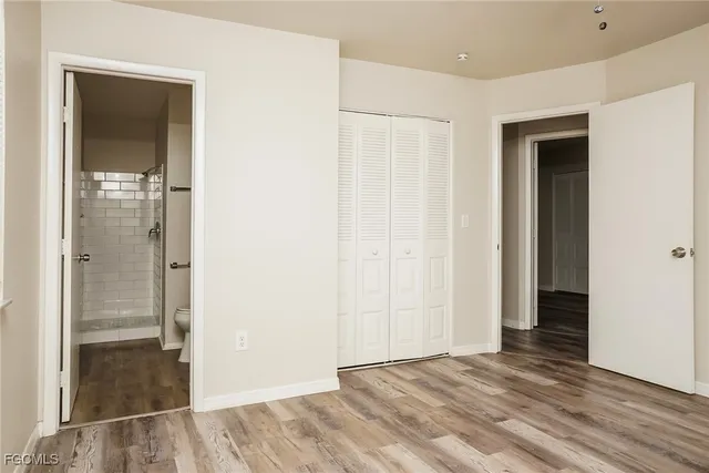 a view of an empty room with wooden floor and a bathroom