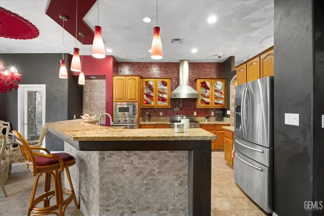 a kitchen with stainless steel appliances kitchen island granite countertop a table chairs in it and wooden floors