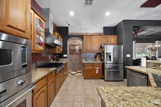 a kitchen with stainless steel appliances granite countertop a refrigerator a stove and a sink with wooden floor
