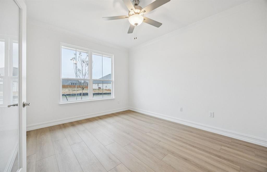 11216 Abbotsbury Road Fort Worth, TX 76052 - Photo 9 of 20 an empty room with wooden floor fan and windows