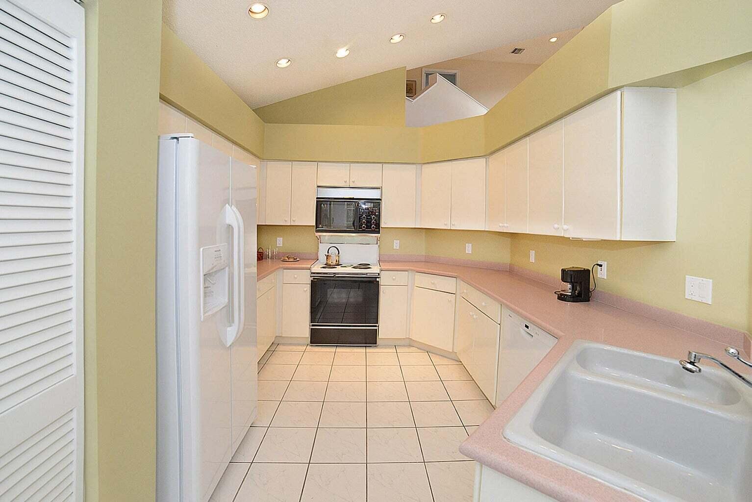 6695 Northwest 25th Court Boca Raton, FL 33496 - Photo 9 of 40 a kitchen with a sink a refrigerator and cabinets