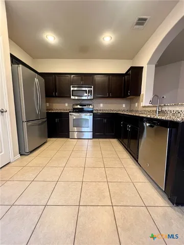 a kitchen with stainless steel appliances kitchen island granite countertop a sink and cabinets