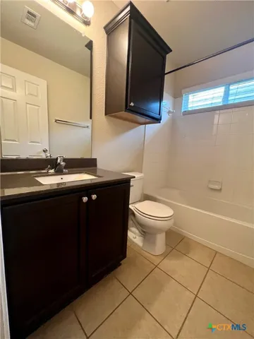 a bathroom with a granite countertop toilet sink and mirror