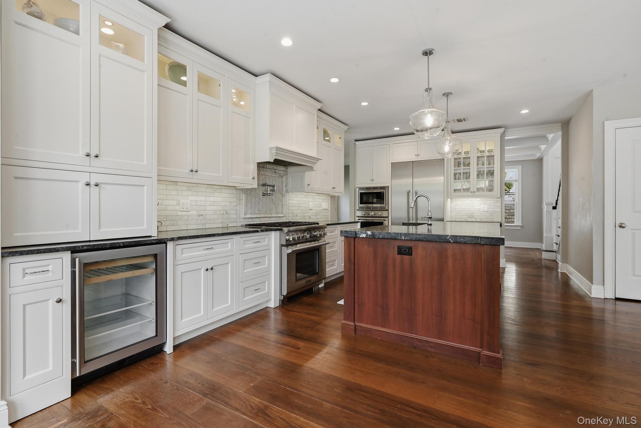 42 Skunks Misery Road Locust Valley, NY 11560 - Photo 12 of 50 Modern kitchen featuring white cabinetry, dark stone countertops, stainless steel appliances, a tile backsplash, and wood-finish flooring