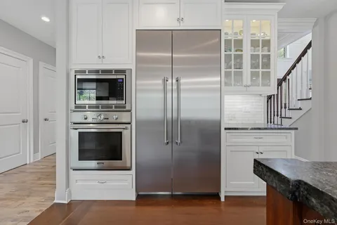 a kitchen with stainless steel appliances kitchen island granite countertop a refrigerator a stove and a sink with wooden floor