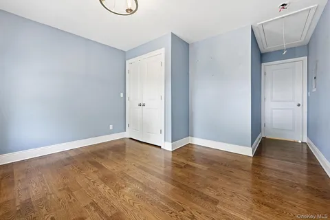 a view of an empty room with wooden floor and closet