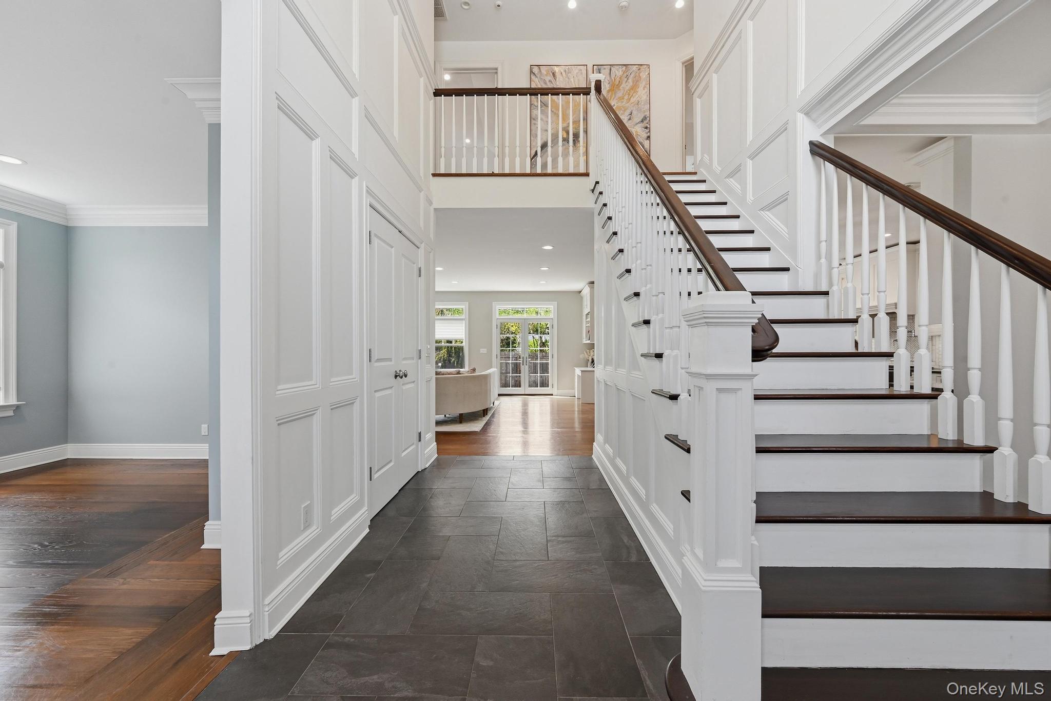 42 Skunks Misery Road Locust Valley, NY 11560 - Photo 3 of 50 Grand two-story foyer featuring a prominent staircase with dark wood-finish treads and handrail, white balusters, and wainscoting
