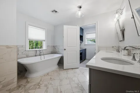 a spacious bathroom with a bathtub sink and a mirror